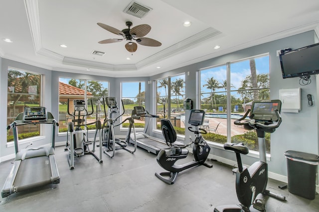 gym with a raised ceiling, ceiling fan, and ornamental molding