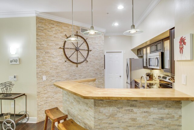 kitchen with kitchen peninsula, a kitchen breakfast bar, appliances with stainless steel finishes, and hardwood / wood-style flooring