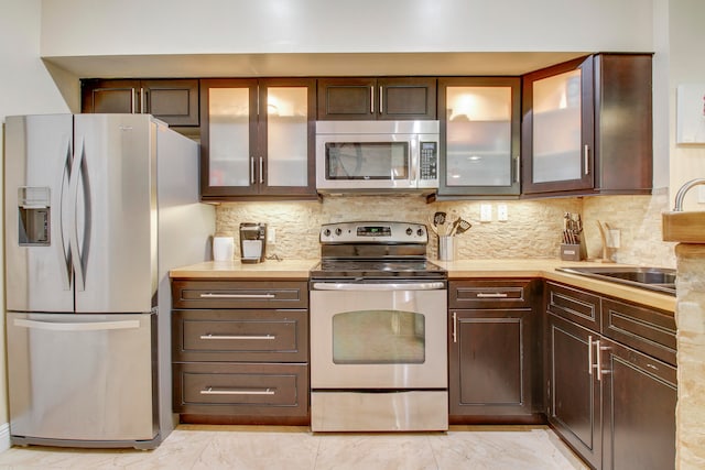 kitchen featuring appliances with stainless steel finishes, decorative backsplash, and dark brown cabinetry