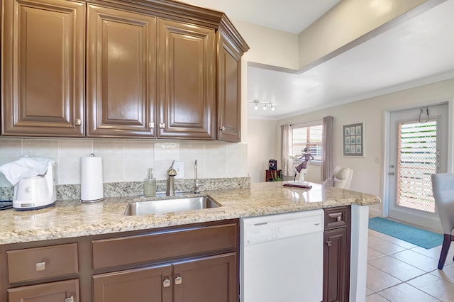 kitchen with light stone counters, light tile patterned floors, decorative backsplash, a sink, and dishwasher