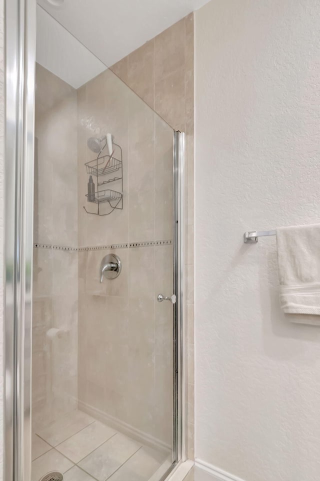 full bath featuring a textured wall and a shower stall