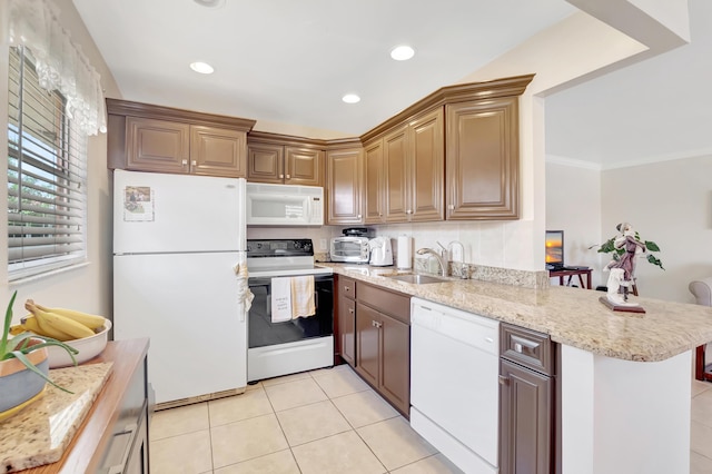 kitchen featuring light tile patterned floors, light stone counters, a peninsula, white appliances, and a sink