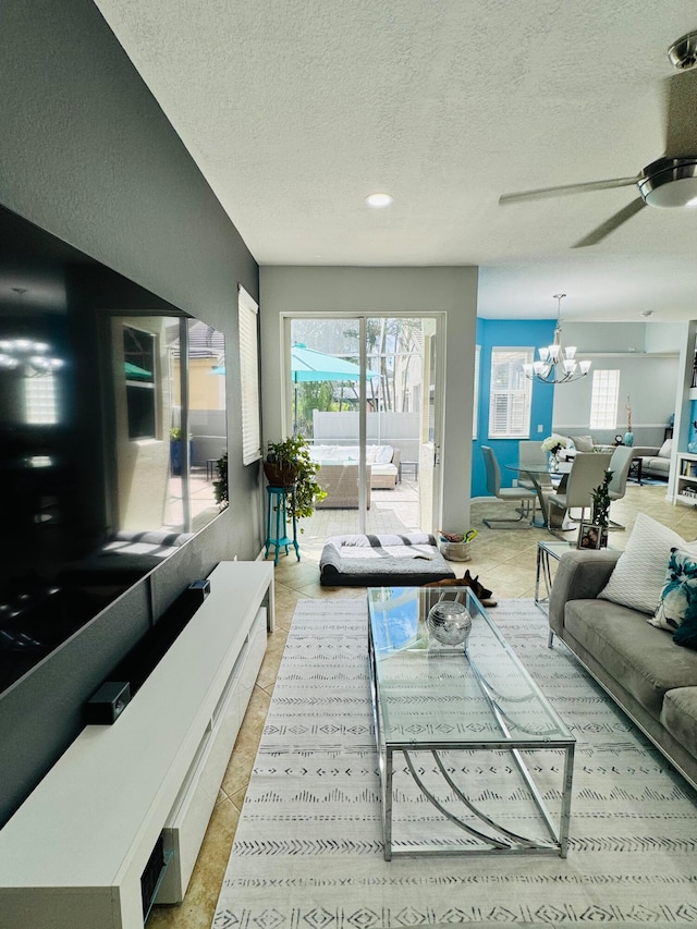 tiled living room with ceiling fan with notable chandelier and a textured ceiling