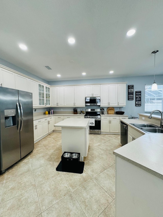 kitchen featuring white cabinetry, a kitchen island, sink, hanging light fixtures, and appliances with stainless steel finishes