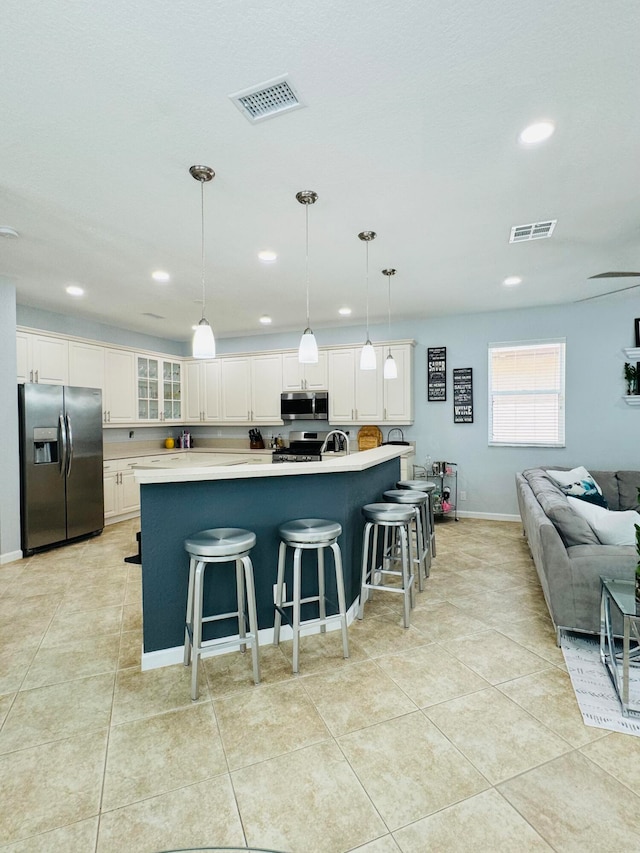 kitchen with white cabinets, a breakfast bar area, stainless steel appliances, and pendant lighting