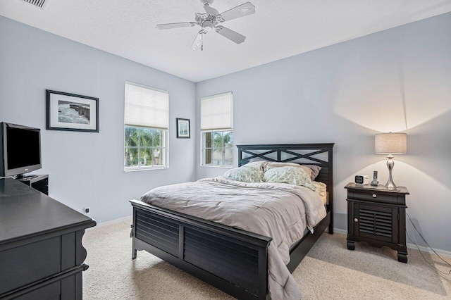 bedroom featuring a textured ceiling, ceiling fan, and light colored carpet