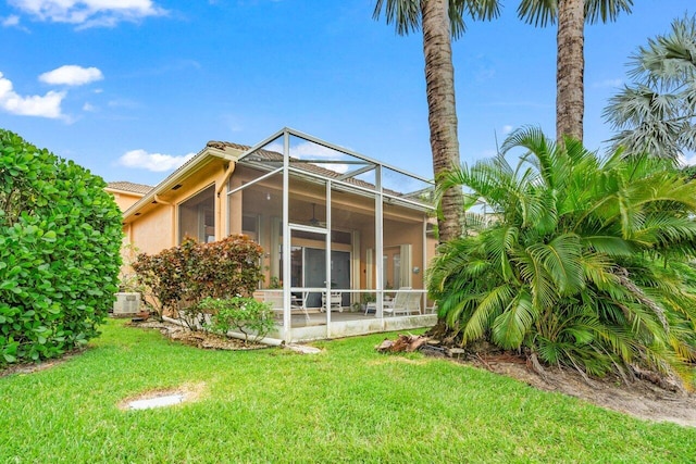 back of house with a lanai, a patio area, and a lawn