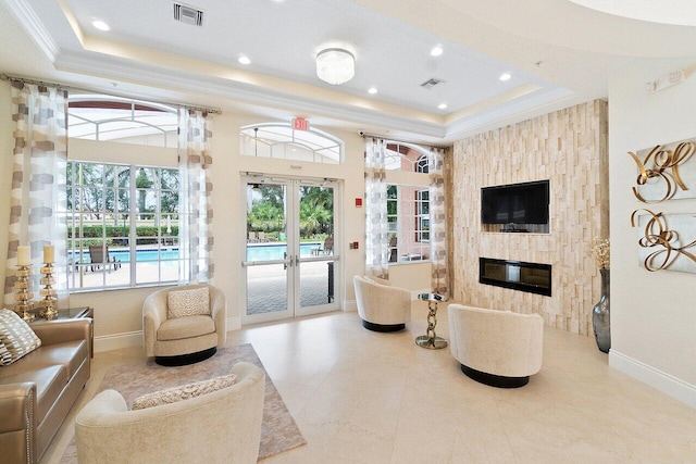 living room featuring a fireplace, french doors, crown molding, and a tray ceiling