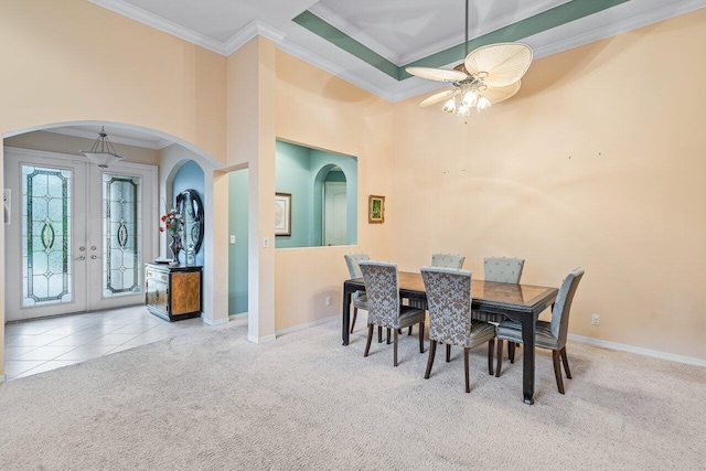 dining space with crown molding, ceiling fan, light carpet, and a high ceiling