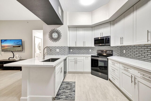 2801 Riverside Dr Unit 203-S, Coral Springs, FL 33065 - kitchen featuring appliances with stainless steel finishes, a sink, a peninsula, light wood-style flooring, and decorative backsplash