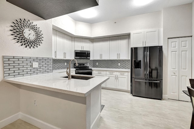 kitchen featuring sink, appliances with stainless steel finishes, light stone counters, white cabinets, and kitchen peninsula