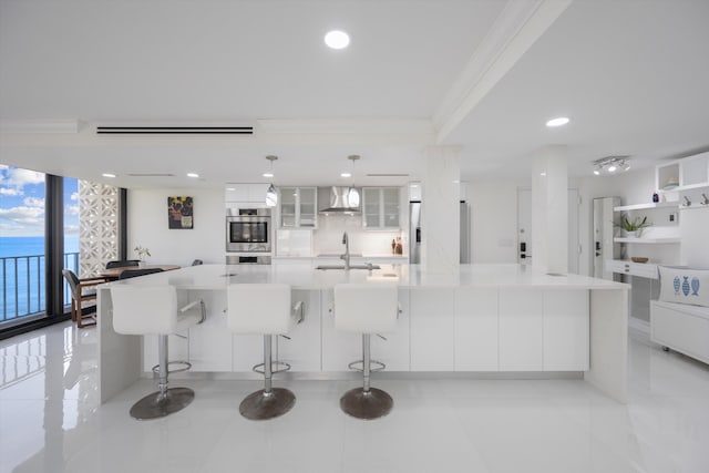 kitchen featuring a spacious island, wall chimney exhaust hood, and hanging light fixtures