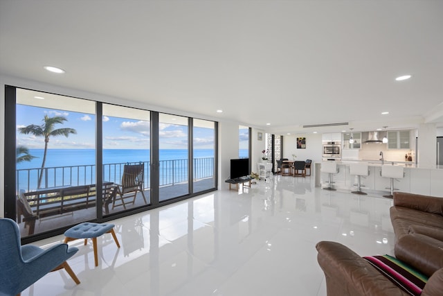 living room featuring expansive windows, light tile patterned flooring, and sink