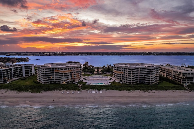 aerial view at dusk featuring a view of the beach and a water view