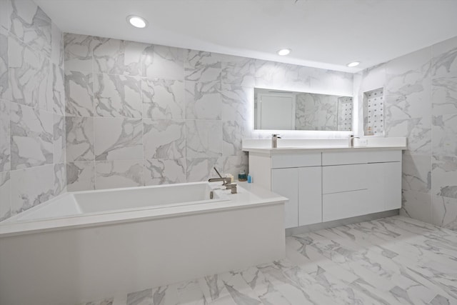 bathroom with tile walls, vanity, and a bath