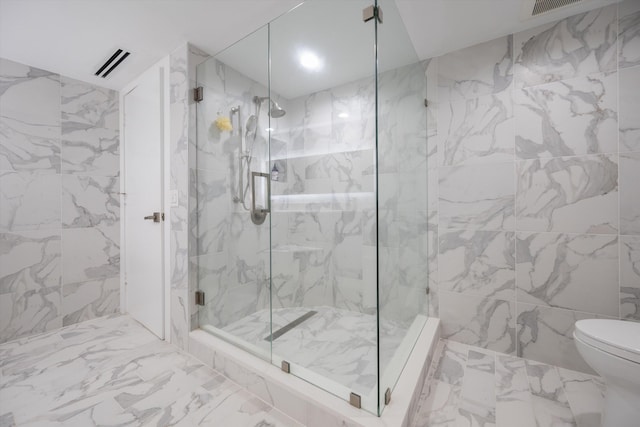 bathroom featuring toilet and a shower with shower door