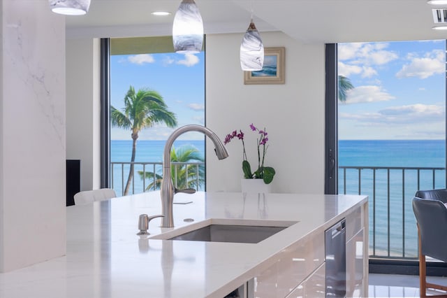 kitchen featuring hanging light fixtures, a healthy amount of sunlight, a water view, and sink