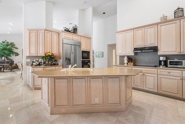 kitchen featuring black appliances, light brown cabinetry, and a kitchen island with sink