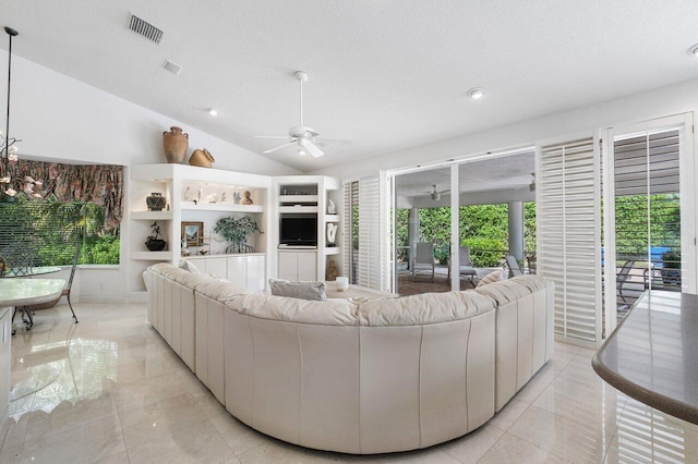 living room with lofted ceiling, ceiling fan with notable chandelier, and a textured ceiling