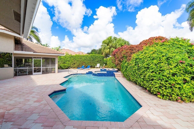 view of swimming pool with a patio, a sunroom, and an in ground hot tub