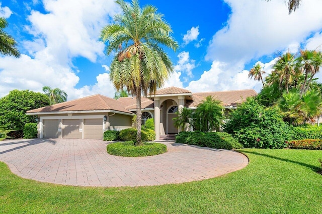 mediterranean / spanish home featuring a garage and a front yard