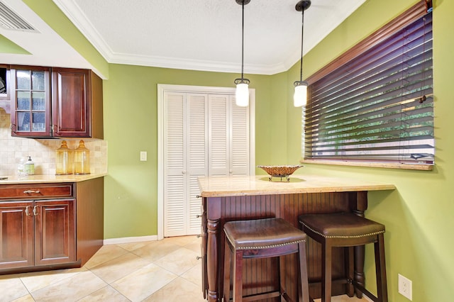 kitchen with pendant lighting, a textured ceiling, a breakfast bar area, and backsplash