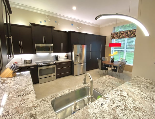 kitchen with light stone countertops, pendant lighting, appliances with stainless steel finishes, sink, and light tile patterned flooring