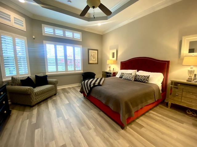 bedroom with a tray ceiling, multiple windows, wood-type flooring, and ceiling fan