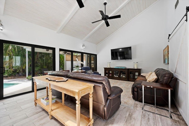 living room with beam ceiling, high vaulted ceiling, a barn door, ceiling fan, and light wood-type flooring