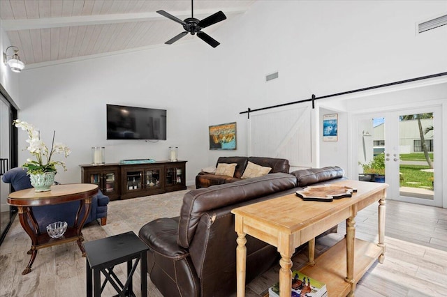 living room featuring a barn door, high vaulted ceiling, light hardwood / wood-style floors, ceiling fan, and beam ceiling