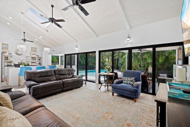 living room featuring high vaulted ceiling, ceiling fan with notable chandelier, a skylight, beam ceiling, and light hardwood / wood-style floors