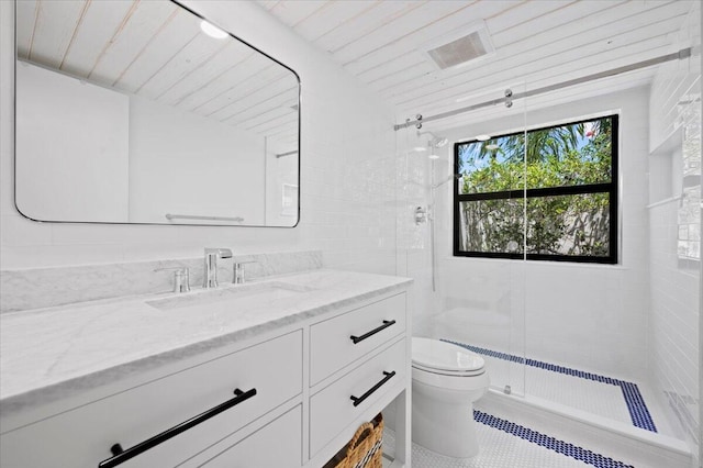 bathroom with toilet, tile patterned floors, vanity, a tile shower, and wooden ceiling