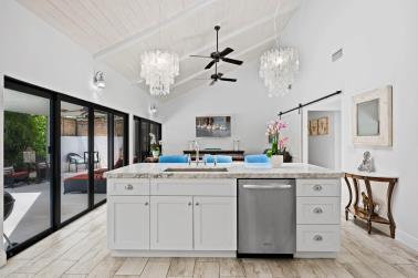 kitchen with dishwasher, sink, high vaulted ceiling, white cabinetry, and a barn door