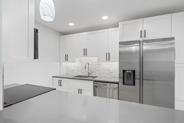 kitchen with stainless steel appliances, sink, white cabinets, and tasteful backsplash