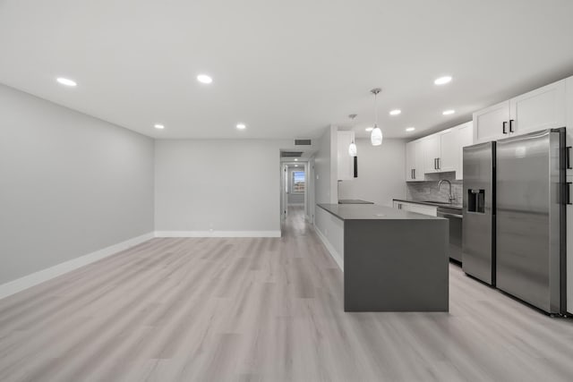 kitchen featuring appliances with stainless steel finishes, tasteful backsplash, light hardwood / wood-style floors, kitchen peninsula, and white cabinets