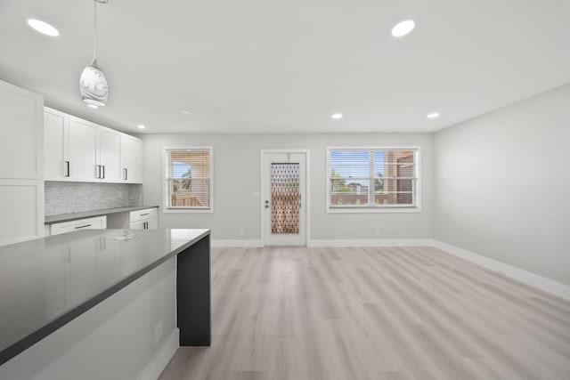 kitchen featuring white cabinets, pendant lighting, decorative backsplash, and light hardwood / wood-style floors