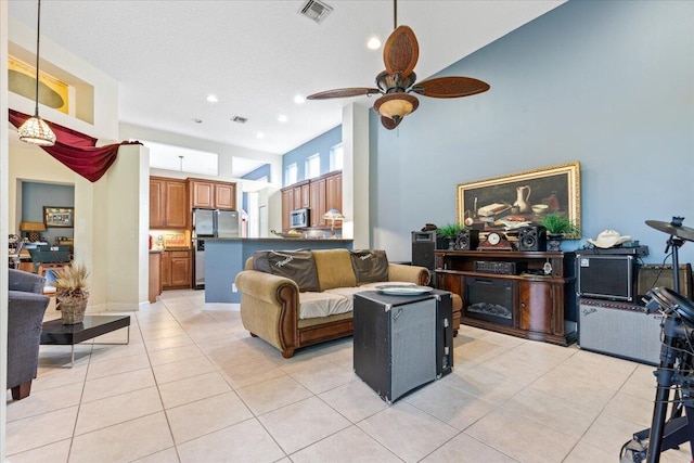 living room featuring a towering ceiling, light tile patterned floors, and ceiling fan