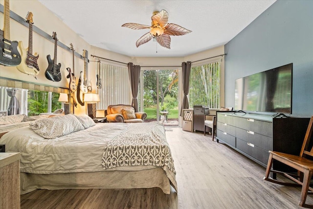 bedroom featuring multiple windows, ceiling fan, hardwood / wood-style flooring, and access to outside