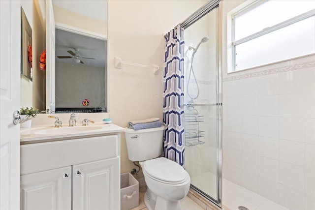 bathroom with vanity, toilet, a shower with shower door, and ceiling fan