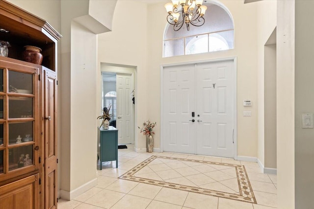 tiled foyer entrance featuring a towering ceiling and a chandelier