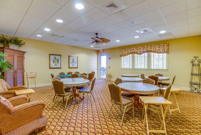 dining area featuring ceiling fan, carpet floors, and a drop ceiling