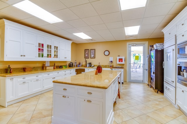 kitchen featuring light stone countertops, a center island, and white cabinetry