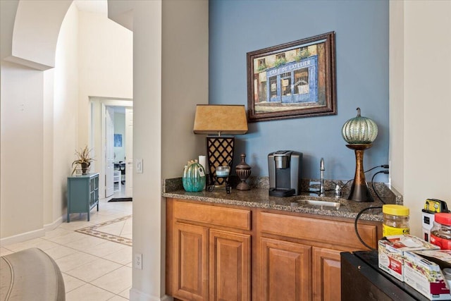 interior space featuring light tile patterned floors, dark stone counters, and sink