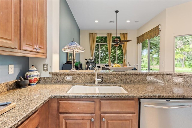 kitchen with pendant lighting, stainless steel dishwasher, light stone counters, and sink