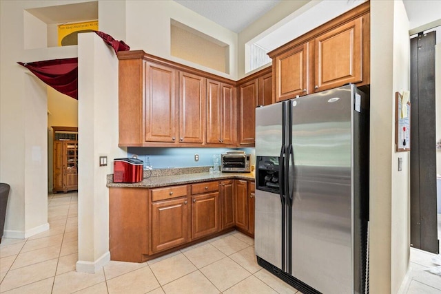 kitchen featuring light stone countertops, stainless steel fridge with ice dispenser, and light tile patterned flooring