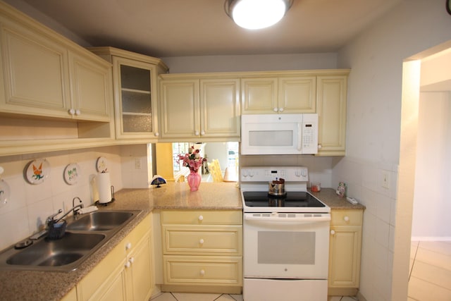 kitchen with backsplash, white appliances, light stone countertops, sink, and light tile patterned flooring