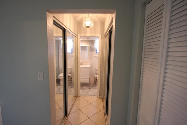 hall with light tile patterned floors and a notable chandelier