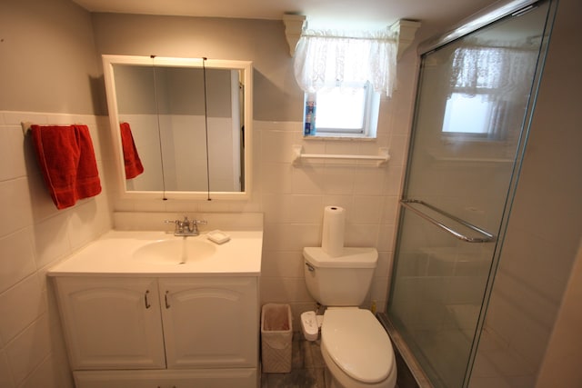 bathroom featuring tile walls, toilet, a shower with door, and vanity