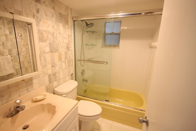 full bathroom with toilet, tile patterned floors, vanity, bath / shower combo with glass door, and tile walls