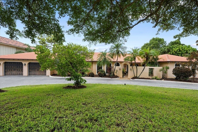 mediterranean / spanish home featuring a garage and a front lawn